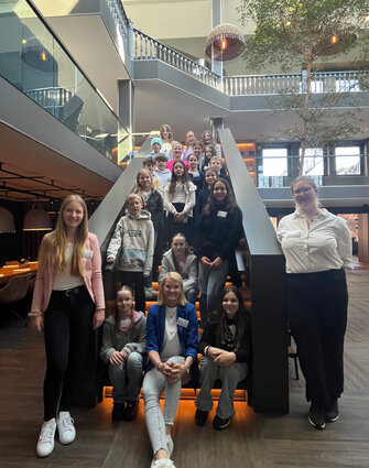 Ein Gruppenfoto, auf welchem 22 Personen zusehen sind. Es sind 19 Kinder und 3 Erwachsene Personen. Die Personen stehen und sitzen auf einer Treppe im ATLANTIC Hotel Landgut Horn.