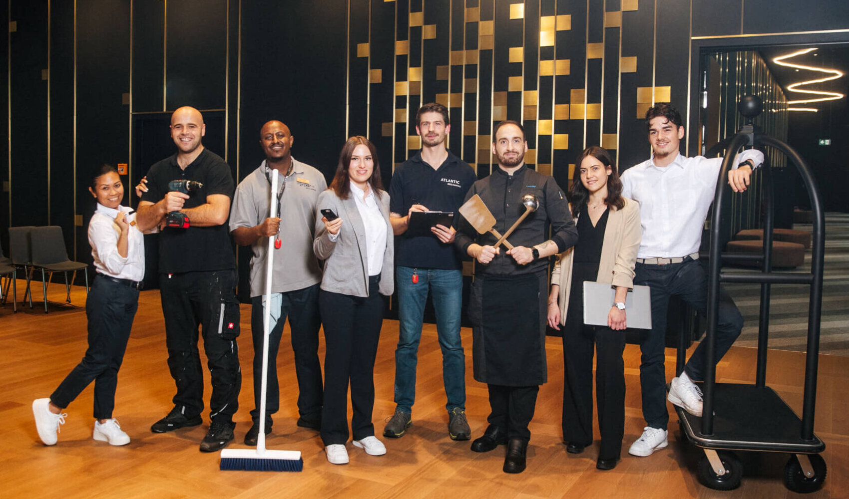 A team picture is formed by eight employees in different uniforms and with different everyday objects.