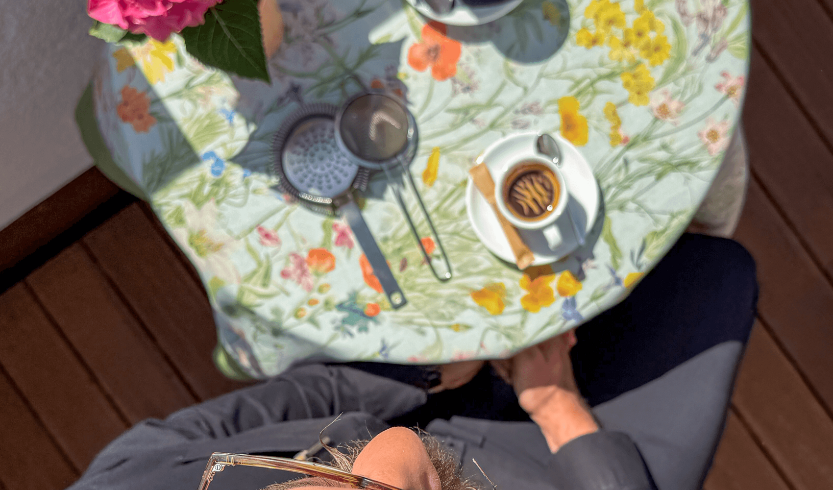Von oben fotografiert ist Igor Pocrnja zu sehen, wie er an einem runden Tisch sitzt. Auf dem Tisch vor ihm stehen ein Espresso, ein Latte Macchiato und eine Topfblume. 