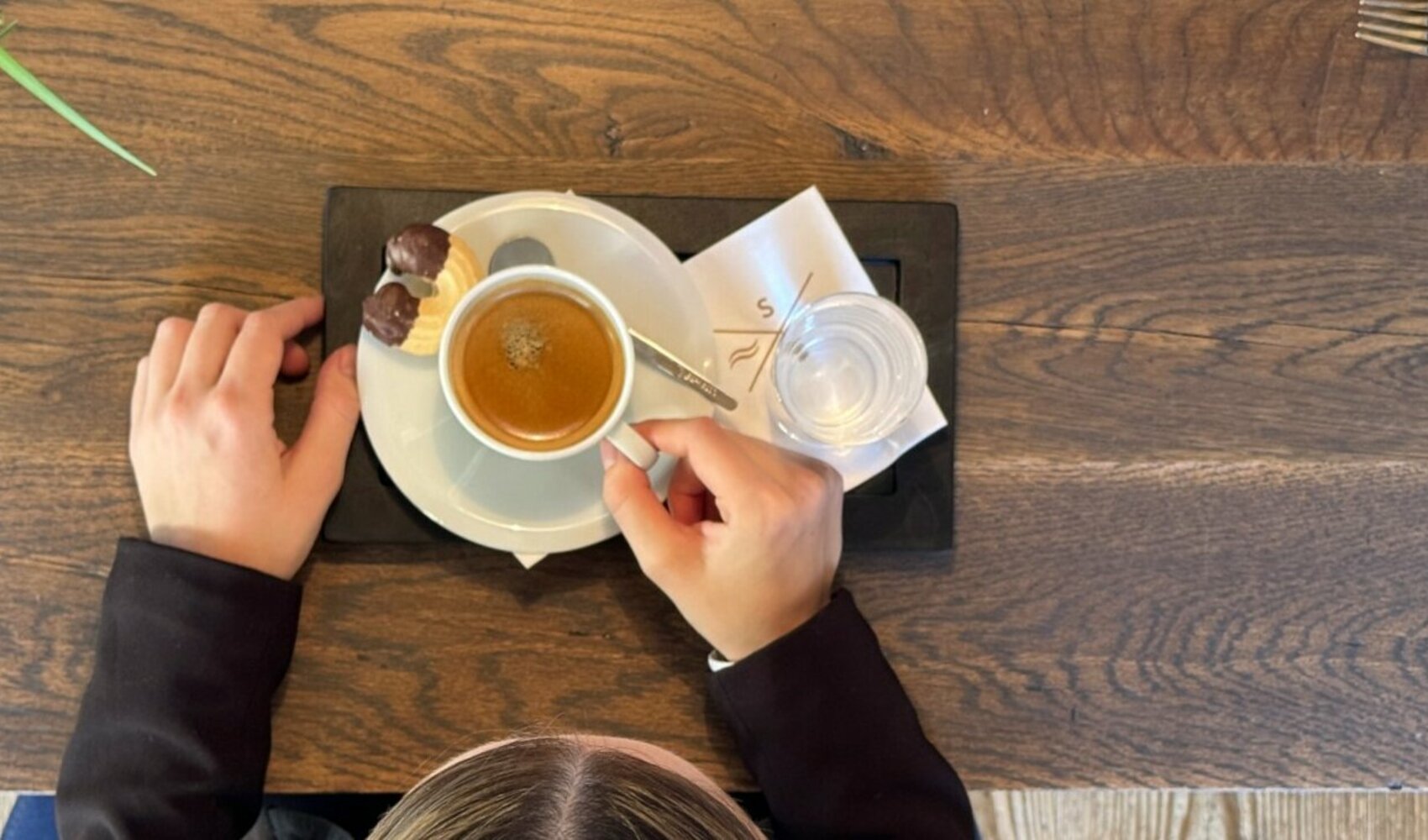 Blick von oben auf den Tisch mit einem Kaffee an dem Nadja Karrer (Restaurant Supervisor, Severin*s – The Alpine Retreat) sitzt