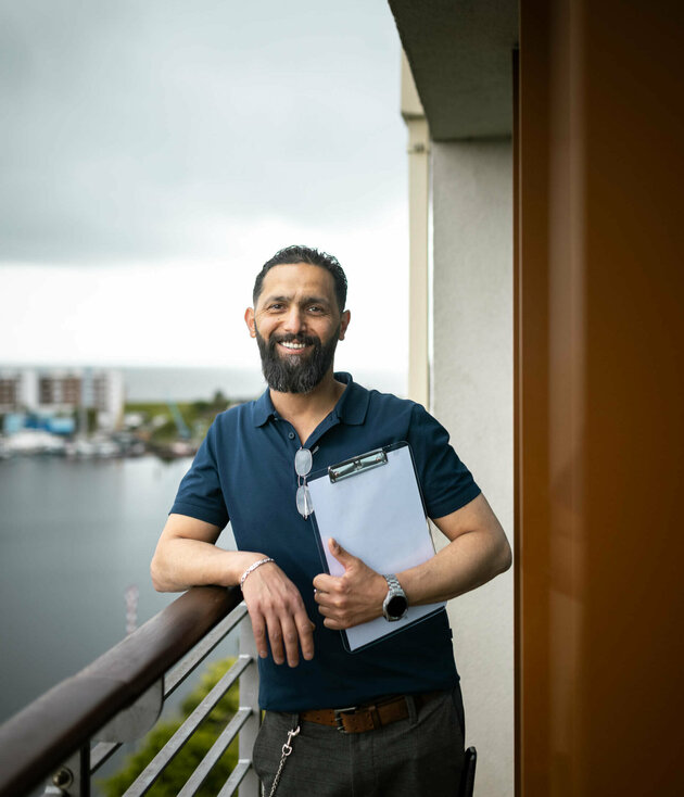 Bilal Madi steht mit einem Klemmbrett auf dem Balkon eines Zimmers