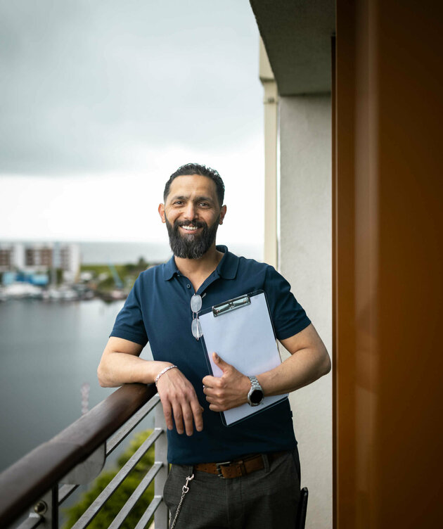 Bilal Madi steht mit einem Klemmbrett auf dem Balkon eines Zimmers