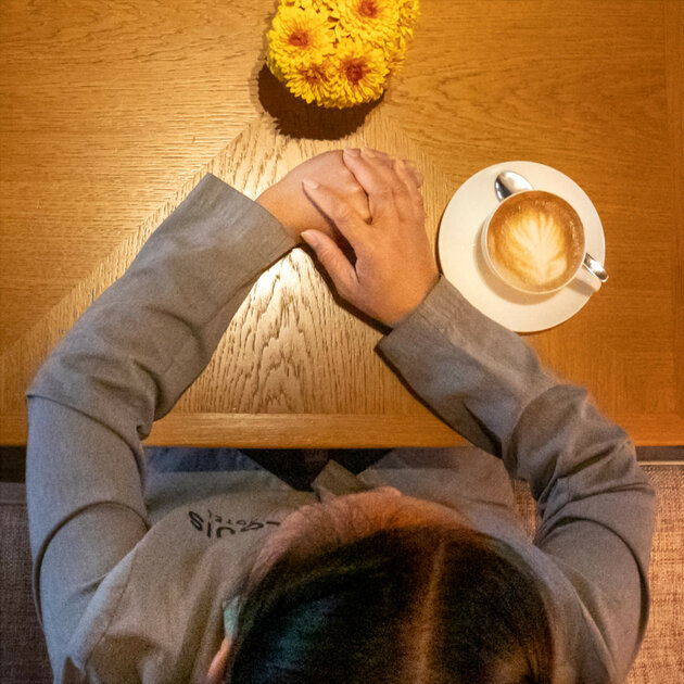 Nikka Vollstädt ist von oben sitztend am Tisch mit einem Kaffee zu sehen