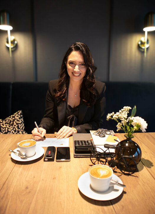 Duygu Saltik (Stellv. Hoteldirektorin, ATLANTIC Hotel Münster) sitzt an einem Tisch mit einer Tasse Kaffee