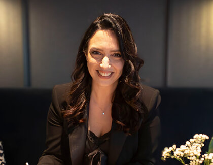 Auf einen Kaffee mit Duygu Saltik (Stellv. Hoteldirektorin, ATLANTIC Hotel Münster) Duygu Saltik (Stellv. Hoteldirektorin, ATLANTIC Hotel Münster) sitzt an einem Tisch auf dem zwei Tassen Kaffee stehen und mehrere persönliche Gegenstände wie ein Notizbuch, Schlüssel und mobiles Telefon zu sehen sind.