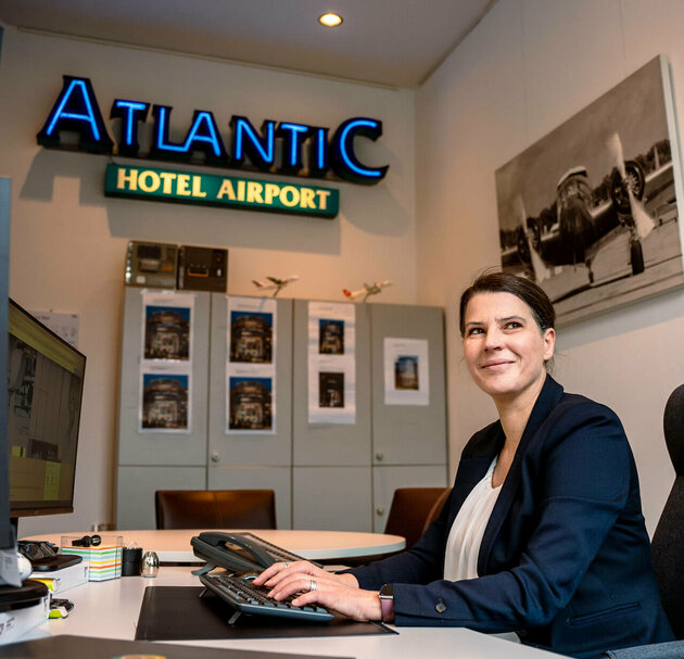 Hotel manager sits at her desk and looks to the side