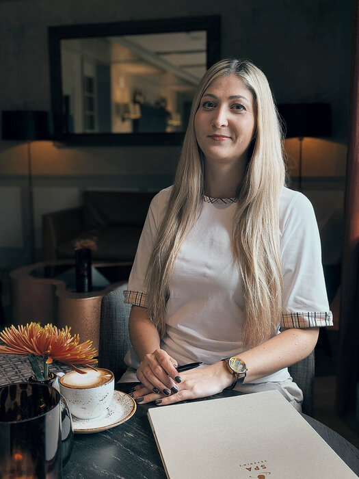 Jana Hohlfeld sitzt mit einem Kaffee am Tisch. 