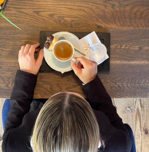 Blick von oben auf den Tisch mit einem Kaffee an dem Nadja Karrer (Restaurant Supervisor, Severin*s – The Alpine Retreat) sitzt