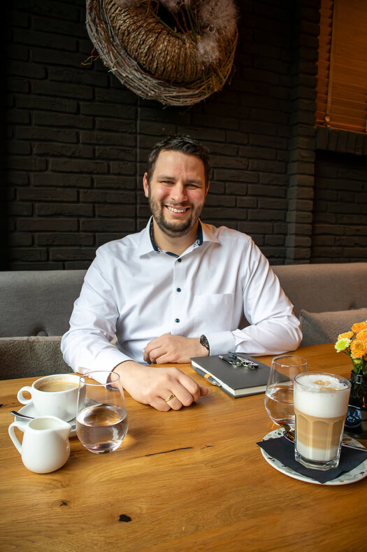 Romano Endres (Stellv. Restaurantleiter, ATLANTIC Hotel Landgut Horn) sitzt an einem Tisch mit einer Tasse Kaffee